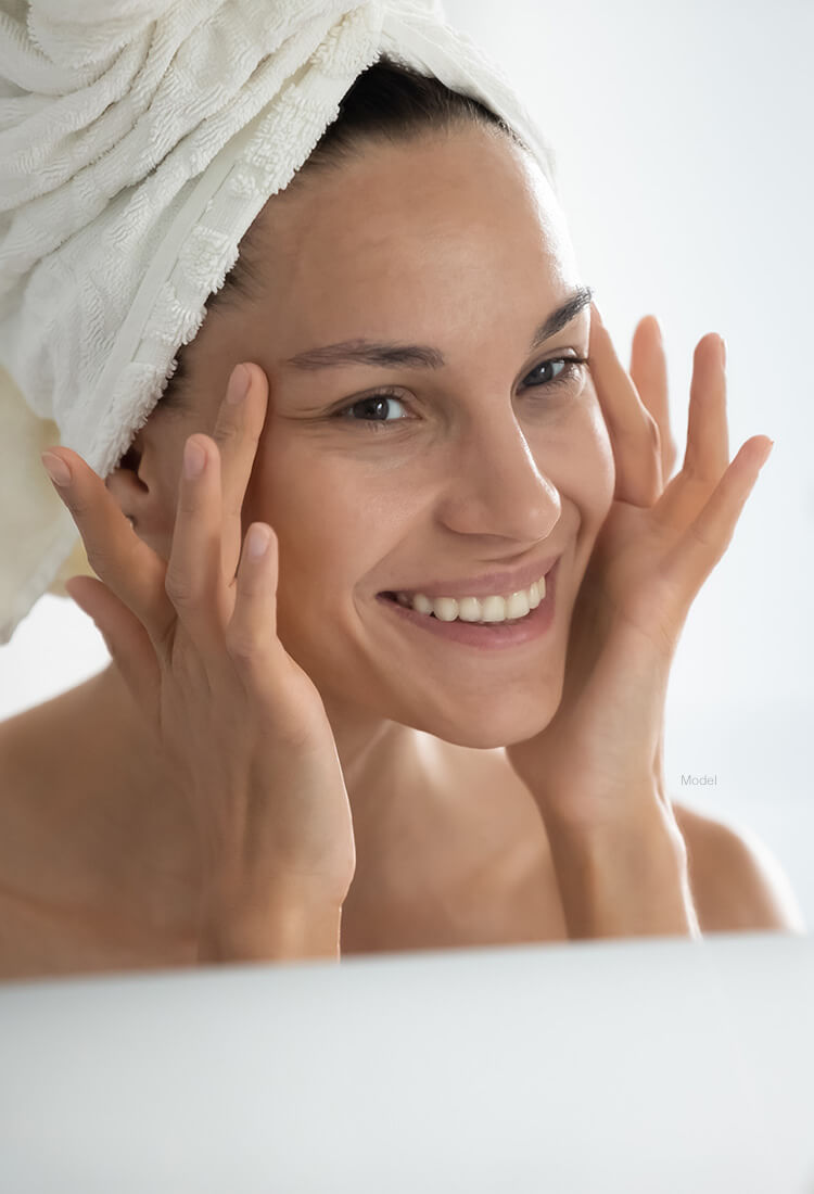 Woman with clear face looking in mirror